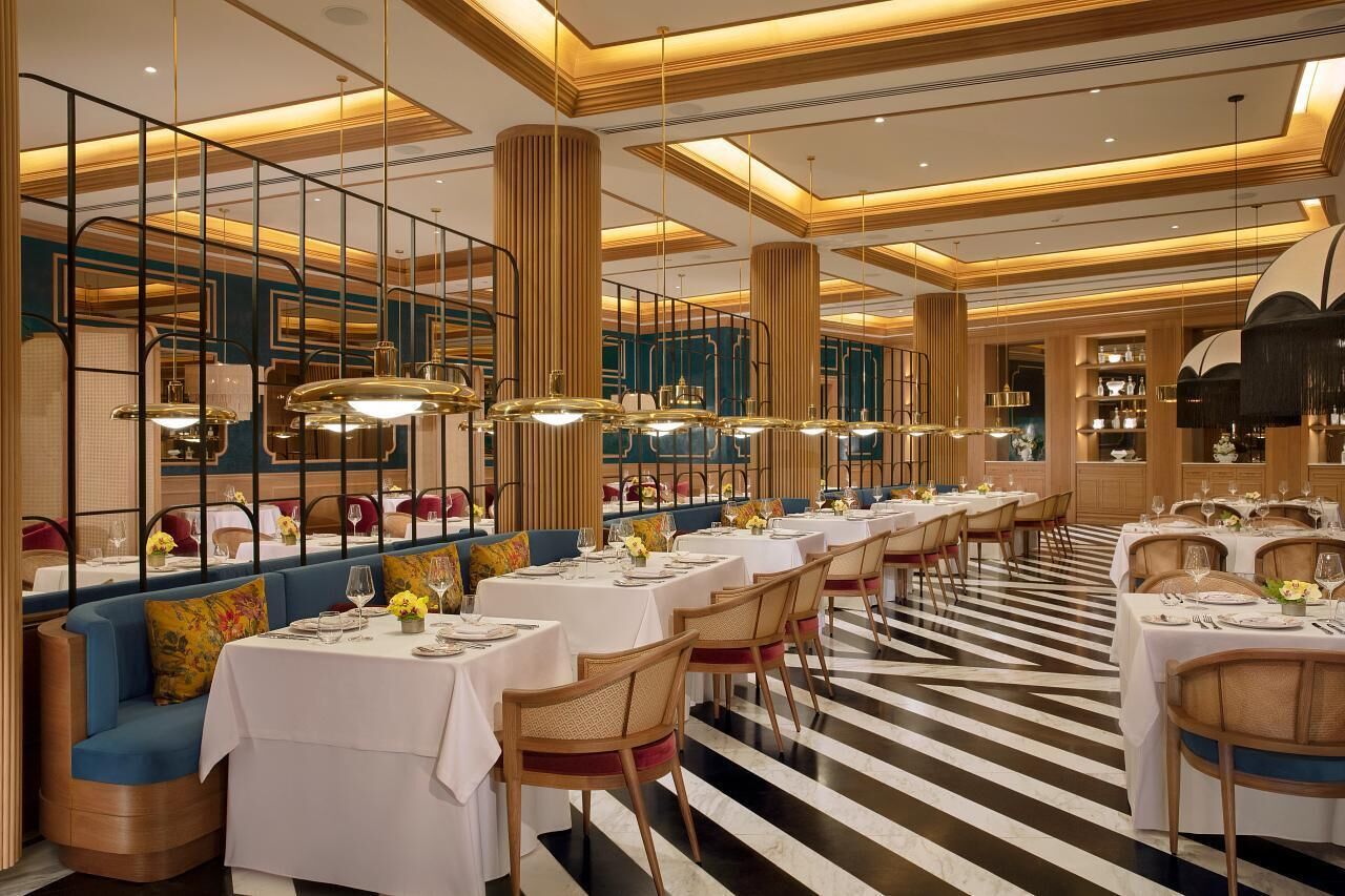 Un restaurante con un amplio comedor, varias mesas y un suelo a rayas.