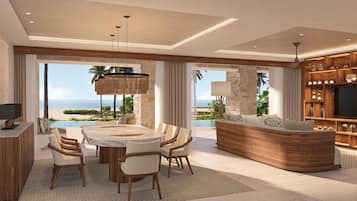 Un vaste espace de vie comprenant une grande table à manger, des sièges confortables, un meuble de rangement intégré pour les appareils multimédias et une vue sur l’océan.