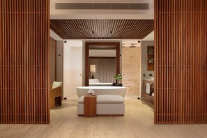 A modern bathroom with a central sink, a mirror, and a wooden partition.