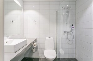 Un baño moderno con lavamanos blanco, inodoro y cabina de ducha con paredes de vidrio.
