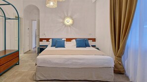 Une chambre d’hôtel avec un lit, une table de chevet, un miroir et un lustre.