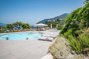 A swimming pool with lounge chairs and umbrellas, surrounded by greenery and overlooking a coastal area. - Hotel Le Axidie, BW Signature Collection (Vico Equense)