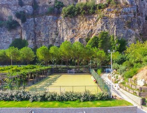 A tennis court with a surrounding fence, trees, and a rocky cliff in the background. - Hotel Le Axidie, BW Signature Collection (Vico Equense)