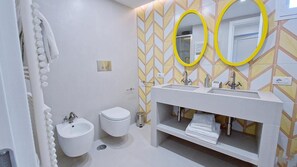 Une salle de bain moderne avec un meuble-lavabo blanc, deux vasques, un bidet et des toilettes.