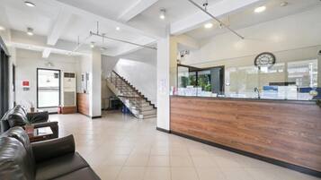 A reception area with a wooden reception desk, a staircase, and a seating area with leather sofas.