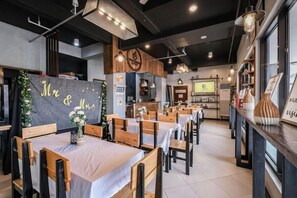 A restaurant with wooden tables and chairs, a chalkboard with 'Mr & Mrs' written on it, and a kitchen area in the background. - Governor Forbes Inn - Manila City Center by Zuzu (Manila)