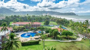 A resort with a pool, palm trees, and a view of the ocean. - Best Western Jaco Beach All Inclusive Resort (Jacó)
