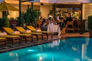 Ein Barbereich am Pool mit Liegestühlen und einer Bar.