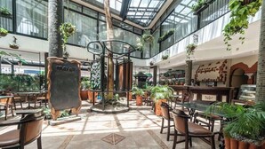 A spacious indoor area with tables and chairs, a central decorative structure, and hanging plants. - Sarova Stanley (Nairobi)