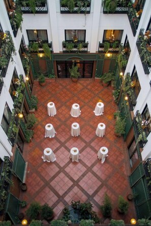A courtyard with tables arranged in a grid, surrounded by balconies with plants. - Sarova Stanley (Nairobi)