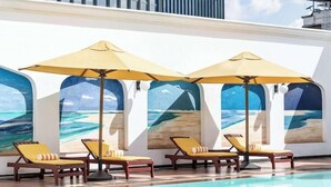 A poolside area with sun loungers and umbrellas, a clear view of the ocean through the windows, and a modern building facade. - Sarova Stanley (Nairobi)