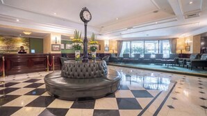 A lobby with a checkered floor, a round seating area, a reception desk, and a large window. - Sarova Stanley (Nairobi)