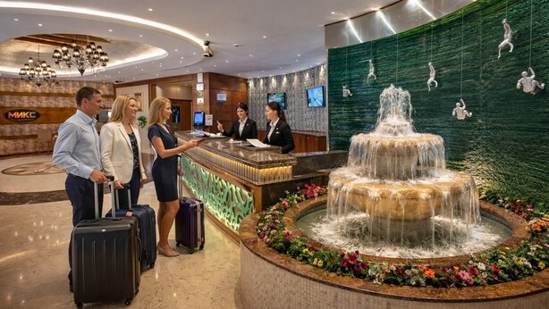 A hotel reception area with a fountain, reception desk, and a wall with climbing figures. - Orchid Hotel Al Barsha Formerly Golden Tulip Al Barsha (Dubai)