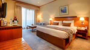 A hotel room with a large bed, bedside tables, a desk, a chair, a television, and a painting on the wall. - Orchid Hotel Al Barsha Formerly Golden Tulip Al Barsha (Dubai)