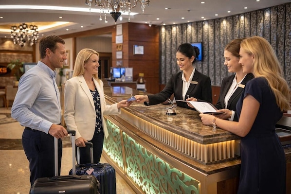 A reception desk with a marble counter, a chandelier, and a patterned wall in a hotel lobby. - Orchid Hotel Al Barsha Formerly Golden Tulip Al Barsha (Dubai)