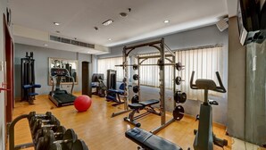 A gym with exercise equipment, a treadmill, and a red exercise ball.