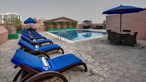 A rooftop pool area with lounge chairs and umbrellas, a pool, and a view of buildings. - Orchid Hotel Al Barsha Formerly Golden Tulip Al Barsha (Dubai)