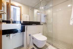 A modern bathroom with a glass shower enclosure, a white toilet, and a vanity with a black countertop. - Unlock Waterfront Edge Business bay (Dubai)