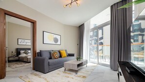 A modern living room with a grey sofa, a coffee table, and a large window with a view of buildings. - Unlock Waterfront Edge Business bay (Dubai)