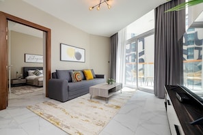Uma sala de estar moderna com um sofá cinzento, uma mesa de centro e uma janela grande com vista para edifícios.