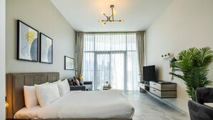 A modern hotel room with a large bed, a TV, a desk, and a plant. - Unlock Waterfront Edge Business bay (Dubai)