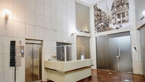 A lobby with a reception desk, elevators, and a large historical mural on the wall.