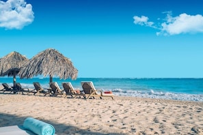 A beach with sun loungers and thatched umbrellas. - Joia Bavaro by Iberostar - Adults Only (Punta Cana)