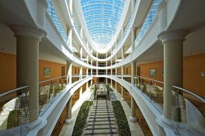 A multi-level atrium with a glass ceiling, white columns, and a central staircase. - Joia Bavaro by Iberostar - Adults Only (Punta Cana)