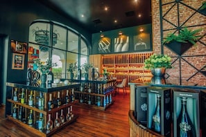A bar with wooden shelves, a brick wall, and a large window. - Joia Bavaro by Iberostar - Adults Only (Punta Cana)