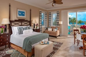 Habitación de hotel con cama, sofá, comedor y balcón con vistas.