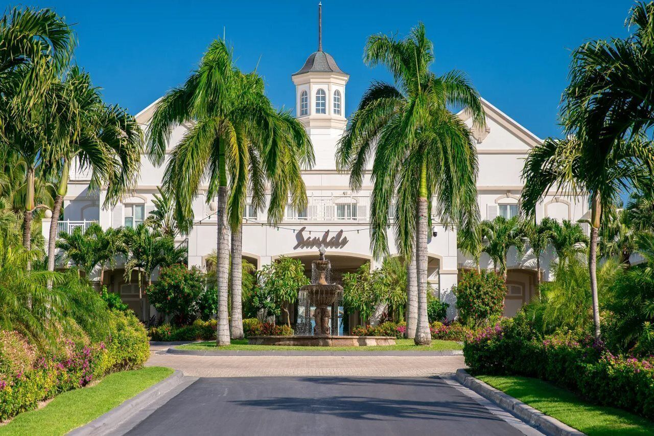 A hotel with a central tower, palm trees, and a fountain.