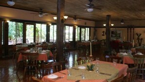 A restaurant with wooden ceiling, large windows, and tables set for dining. - Hacienda La Pacifica (Cañas)