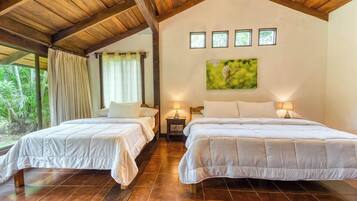 A hotel room with two beds, a large window, and a painting on the wall.