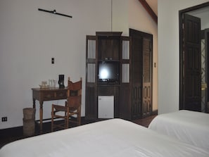 A hotel room with a bed, a desk with a chair, a television, and a wardrobe. - Hacienda La Pacifica (Cañas)