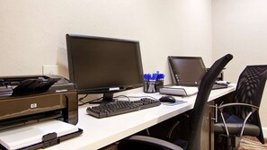 A workspace with a desktop computer, a laptop, a printer, and a chair. - Spark by Hilton Fort Myers (Fort Myers)