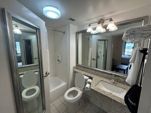 Un baño moderno con ducha, dos inodoros, un lavabo y un espejo grande.