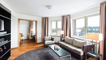 Une chambre d’hôtel moderne équipée d’un canapé, de fauteuils, d’une table basse, d’un téléviseur et d’une bibliothèque.