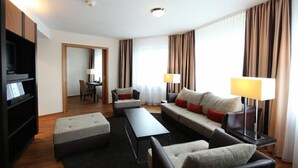 Une chambre d’hôtel moderne comprenant un canapé, une table basse, un téléviseur et un coin repas.