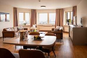 Un salon moderne avec un coin repas, de grandes fenĂŞtres et une vue sur la ville.