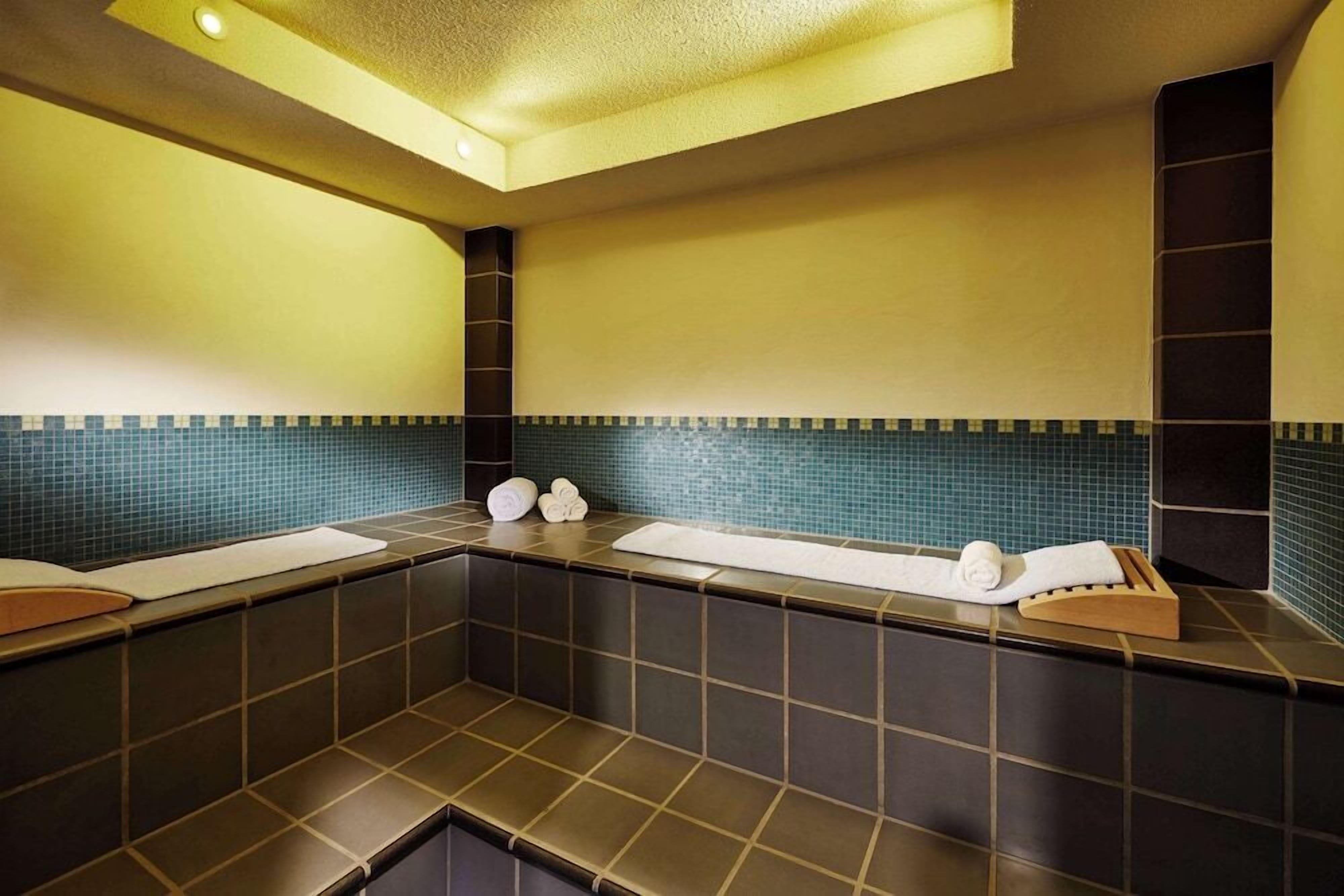 Ein modernes Badezimmer mit dunklen Fliesen, einer blauen Fliesenspiegel und einem hölzernen Handtuchhalter.