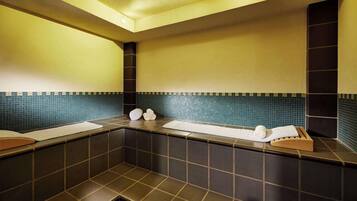 Ein modernes Badezimmer mit dunklen Fliesen, einer blauen Fliesenspiegel und einem hölzernen Handtuchhalter.