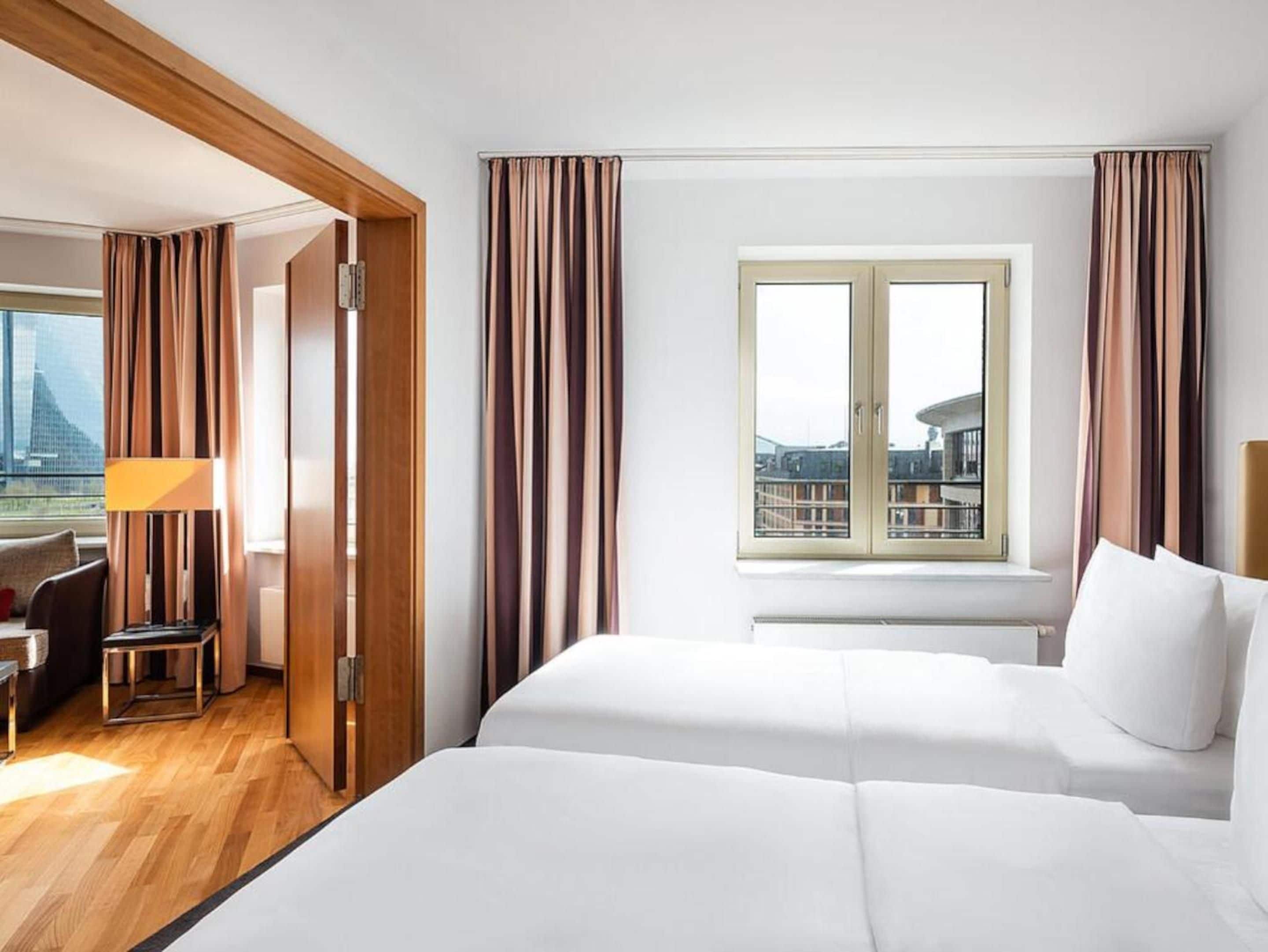 Habitación de hotel con cama, escritorio y vista a la ciudad.