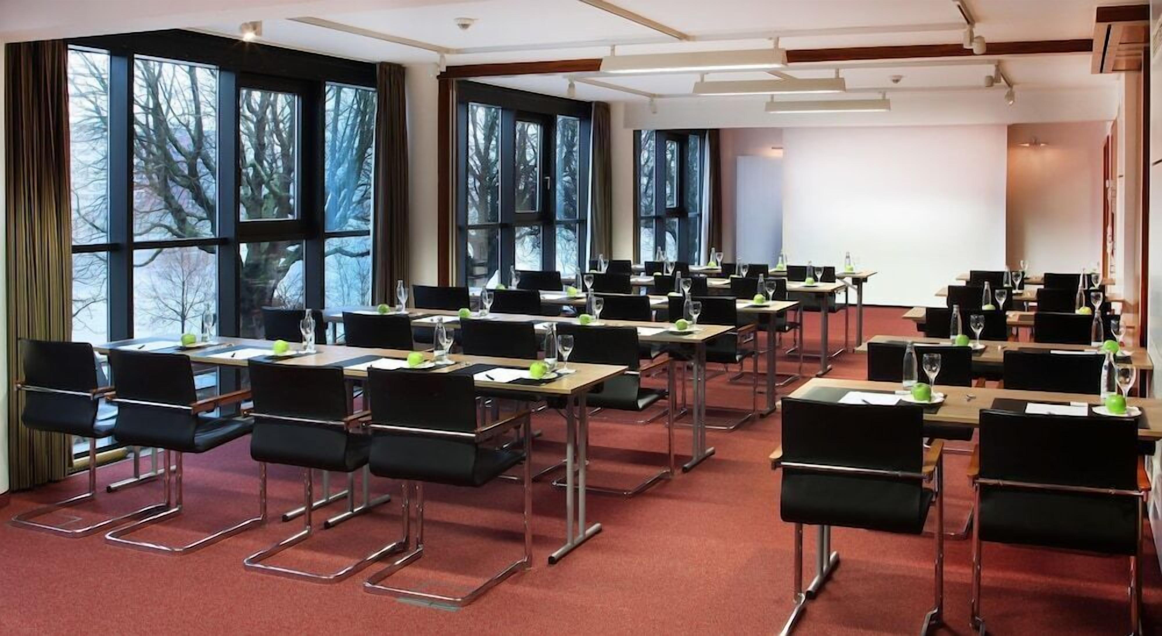Ein Konferenzraum mit Tischen, Stühlen und großen Fenstern.