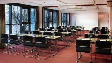 Ein Konferenzraum mit Tischen, Stühlen und großen Fenstern.