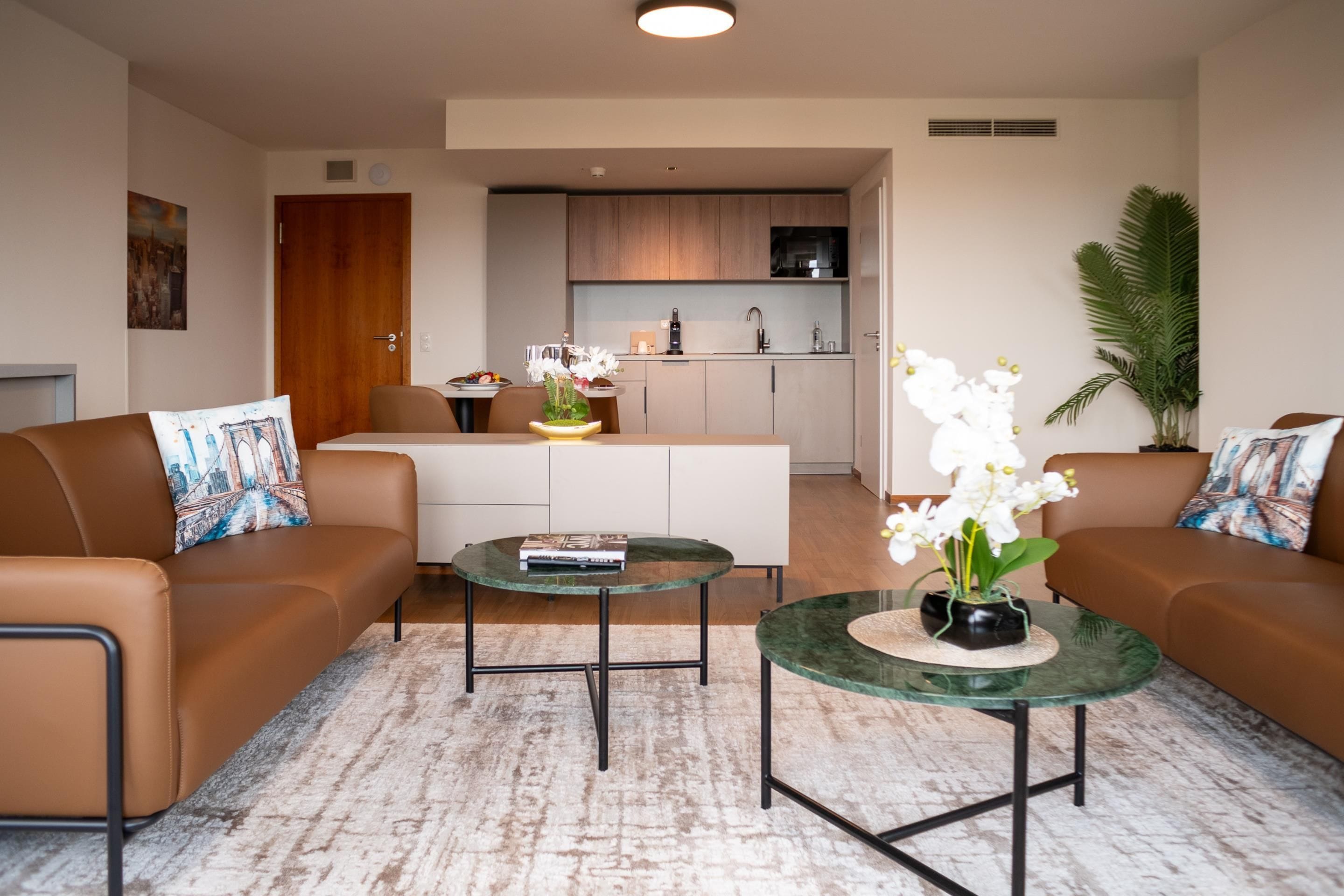 A modern living room with two sofas, a coffee table, and a dining area with a kitchen in the background.