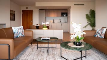 A modern living room with two sofas, a coffee table, and a dining area with a kitchen in the background.