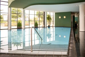 An indoor swimming pool with clear glass walls, a metal ladder, and a tiled floor. - Main Plaza Suite Tower, WorldHotels Elite (Frankfurt)