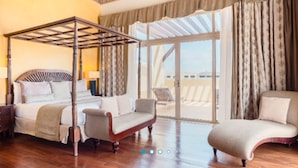 A room with a four-poster bed, a sofa, a chair, and a balcony with curtains. - Iberostar Waves Rose Hall Beach All Inclusive (Montego Bay)