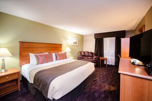 A hotel room with a large bed, a leather armchair, a small table, a television, and a desk. - Ottawa Kanata Hotel and Conference Centre (Ottawa)