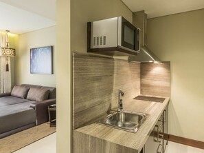 A compact kitchenette with a stainless steel sink, a microwave, and a built-in stove hood. - The Tower Plaza Hotel Dubai (Dubai)